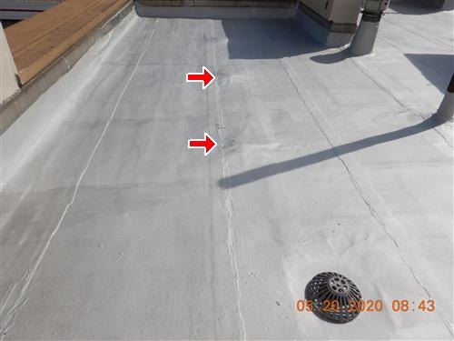 Silver-coated flat roof with a domed drain strainer, two red arrows at a seam, orange date stamp