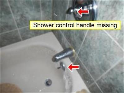 Tub and tiled shower wall with a label reading shower control handle missing and two red arrows at the valve stem and the tub spout.