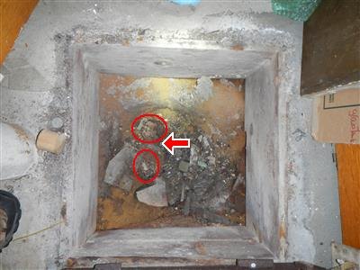 A masonry chimney cleanout opening with fallen debris circled in red.