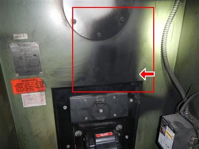 Front of a green furnace with a dark scorched area outlined by a red rectangle above the burner mounting plate.