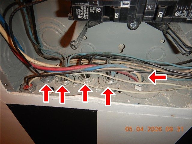 Bottom of an electrical sub panel with cables entering through open connectors, four red arrows beneath and one to the right.