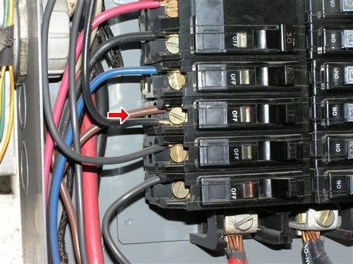 A close view inside an electrical panel with a double-tapped breaker connection arrowed.