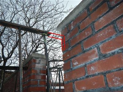 Brick parapet wall with concrete coping and a red bracket marking the coping corner