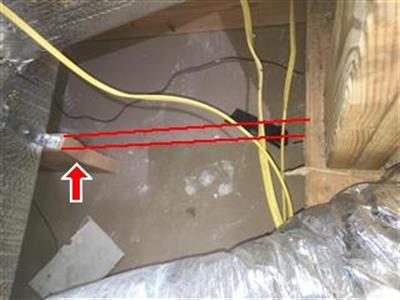Attic framing with red lines along a cut ceiling joist and a red arrow pointing to the cut end.