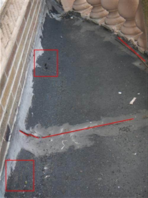 Balcony floor with a worn, cracked tar roof covering next to a brick wall and stone balustrade, with red boxes and lines marking cracks.