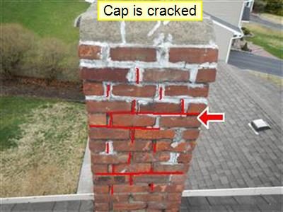 Brick chimney above a roof with the label cap is cracked and red lines tracing cracked mortar joints.