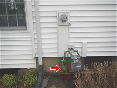 Gas meter and electric meter on white siding with a red box and arrow marking the gas shut-off valve.