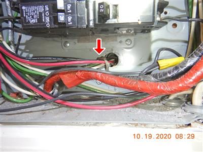 Inside a breaker panel with a red arrow pointing to a cable connector below the breakers.