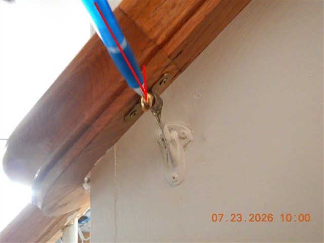 Underside of a wood handrail where it meets a wall bracket, with a red line pointing at a loose screw.