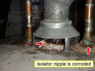 Base of a gas water heater draft hood with rust and corrosion, labelled 
