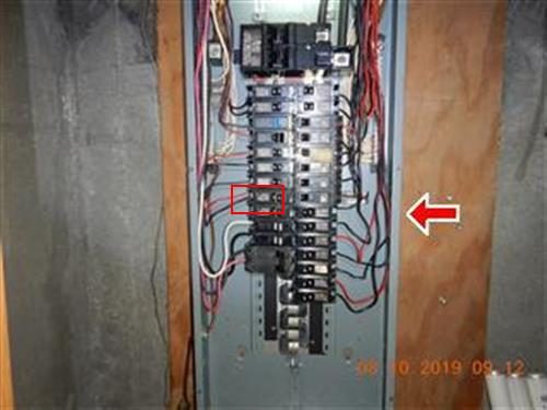 Open main electrical panel with a red box around one breaker on the left side and a red arrow at the right.