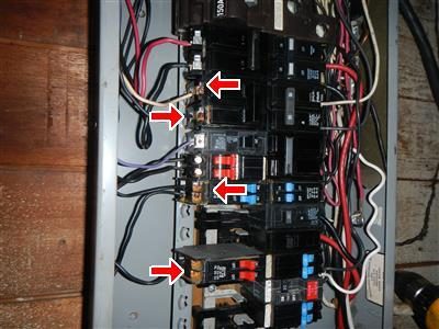 Column of circuit breakers in a main panel with five red arrows pointing at breaker terminals showing corrosion.