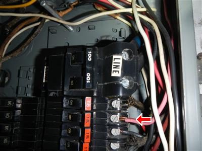 Close view inside a panel labelled LINE with a red arrow at a breaker terminal holding two conductors.