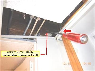 Basement ceiling with a screwdriver pushed into a damaged floor joist, with a red arrow and a report label.