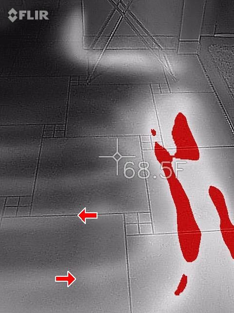 FLIR infrared image of a tiled floor with warm red zones and a 68.5F spot reading, red arrows marking cooler areas.