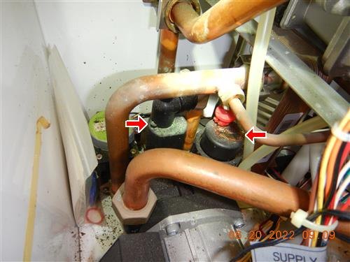 Copper pipes and two circulator pumps with corrosion residue, marked by red arrows