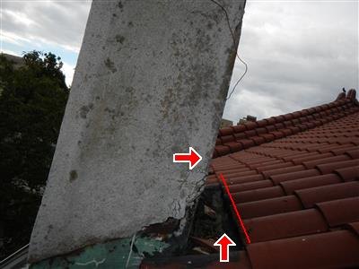 Red arrows at the open joint between a stucco chimney side and a clay tile roof