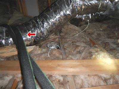 Foil-wrapped flex duct in attic insulation with red arrow, black foam pipe in foreground