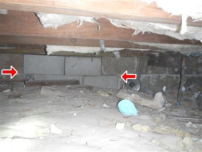 Crawlspace with concrete block supports, fiberglass insulation overhead, red arrows at blockwork