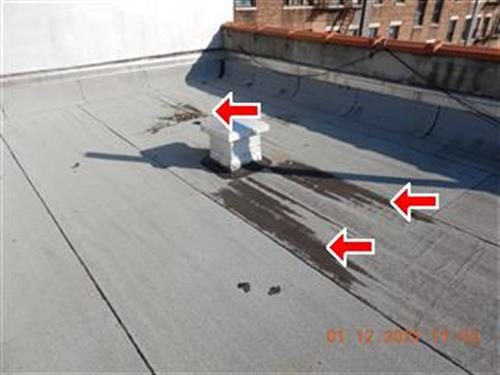 Flat roof with worn dark streaks near the parapet wall and a vent, marked with three red arrows.