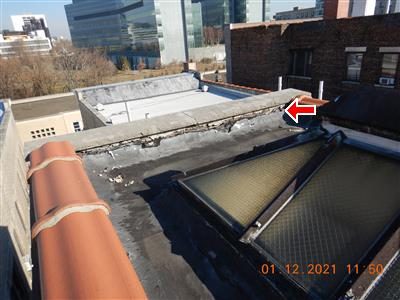 Small roof over an elevator shaft entrance with flashing stopping short of the coping stone, red arrow at the gap.