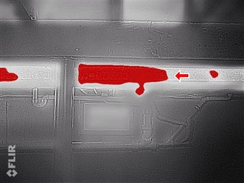 A thermal-camera image with the hot heating pipe showing as a bright red streak across the frame.