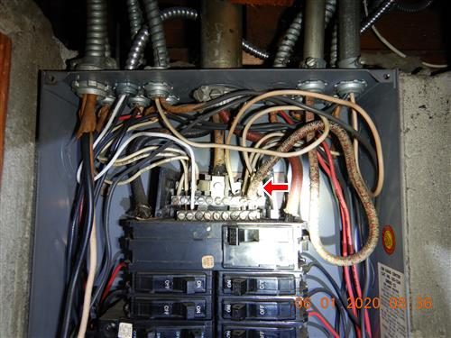 Open main electrical panel with aluminium service wires entering at the top and a red arrow at the neutral bar.