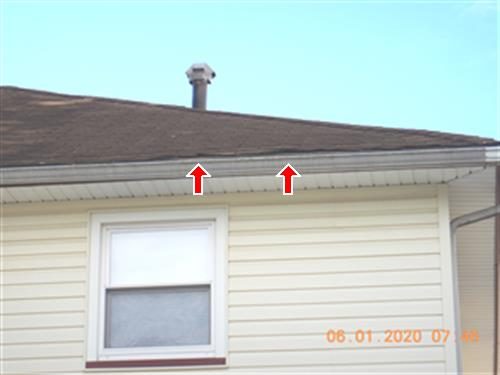 Roof edge over a side wall with two red arrows pointing at raised shingles near the gutter and a metal vent above.