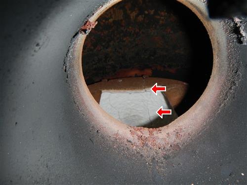 The inside of a round chimney flue with debris blocking part of the opening, circled in red.