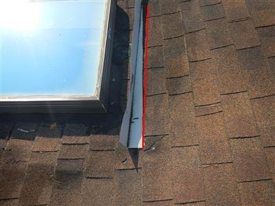 Metal skylight flashing on an asphalt shingle roof with a red line along the raised edge
