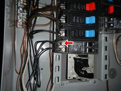 Inside of an electrical panel with breakers and wiring, red arrow at a breaker terminal