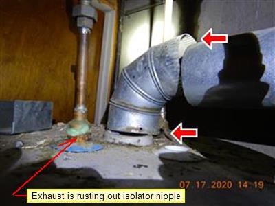 Top of a water heater with a corroded flue connection, three red arrows and a label reading exhaust is rusting out isolator nipple.