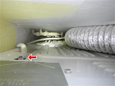 Flexible metal electrical cable entering an appliance housing without a fitting, marked by a red arrow.