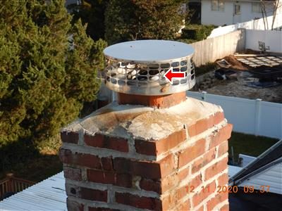 Brick chimney with a stainless steel liner cap on top, red arrow pointing to the liner.