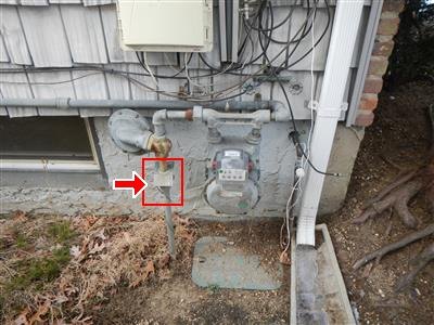 A gas meter and regulator mounted on a house wall, with one component boxed in red.