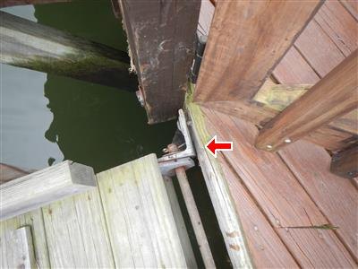 A close view of timber dock and bulkhead members meeting at the waterline, the connection arrowed.