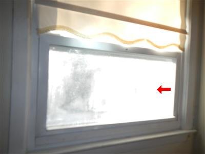 Window with hazy white staining across the glass, red arrow pointing at the pane