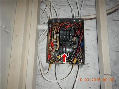 Open sub panel with a tangle of wiring and a red arrow pointing at a breaker in the bottom middle row.