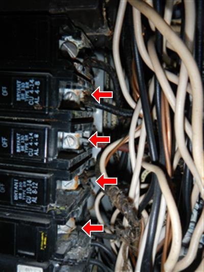 A close view of circuit breakers in an electrical panel with four connection points arrowed.