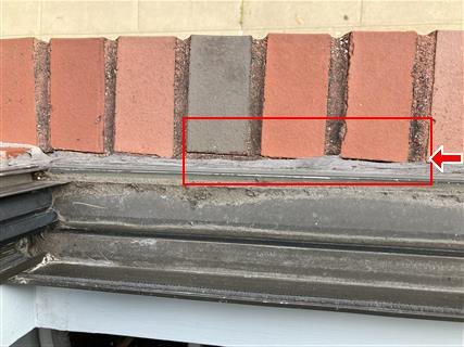 Brick coping above an ornamental painted cornice, with open mortar joints boxed in red.