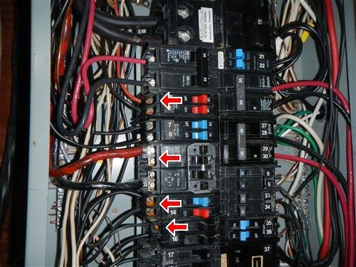An electrical panel with red and black feeder cables and four arrows marking tandem breaker positions.