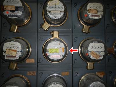 Grid of round glass electric meters with a red arrow marking one meter