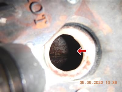 Close-up looking into a round boiler inspection port with a crack marked by a red arrow.
