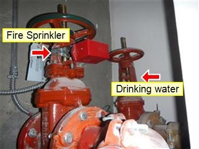 Two red gate valves on large pipes labelled Fire Sprinkler and Drinking water with red arrows.