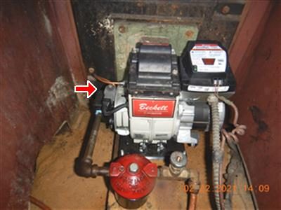 Beckett oil burner mounted on a boiler with a red arrow pointing at the solenoid on the fuel line.