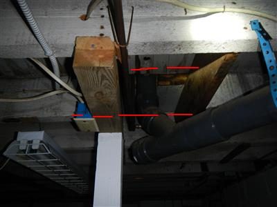 Basement ceiling where a wood joist has been notched around a grey plastic waste pipe, red lines marking the cut.