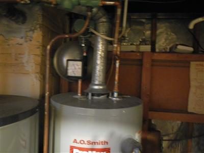 A.O. Smith gas water heater with copper piping and a circulator pump mounted above it in a basement.