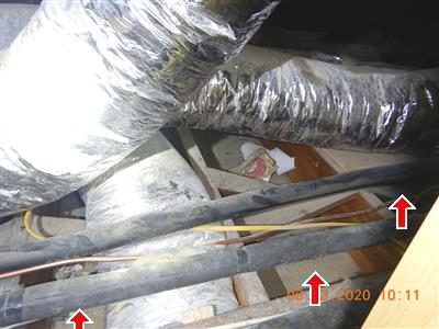 Attic with foil-wrapped ducts over floor joists, red arrows marking bare joist bays with no insulation.