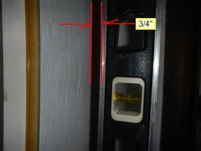 Spirit level held against a bedroom wall showing a 3/4 inch gap at the top, marked with red lines.