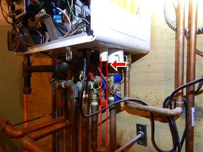 Underside of a wall-hung boiler with copper piping and a red line and arrow marking the condensate line.